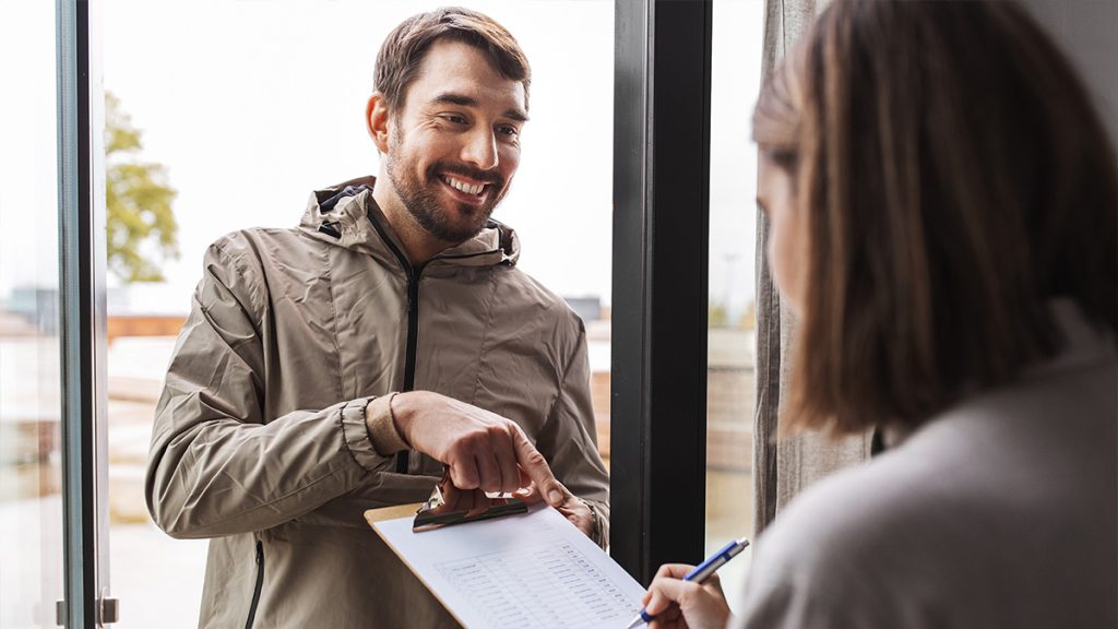 Man pointing at something on a clip board while a woman writes something down