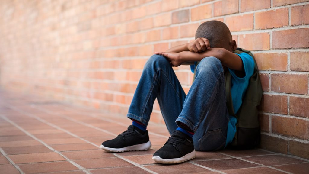 Child sad sitting on the floor with arms crossed