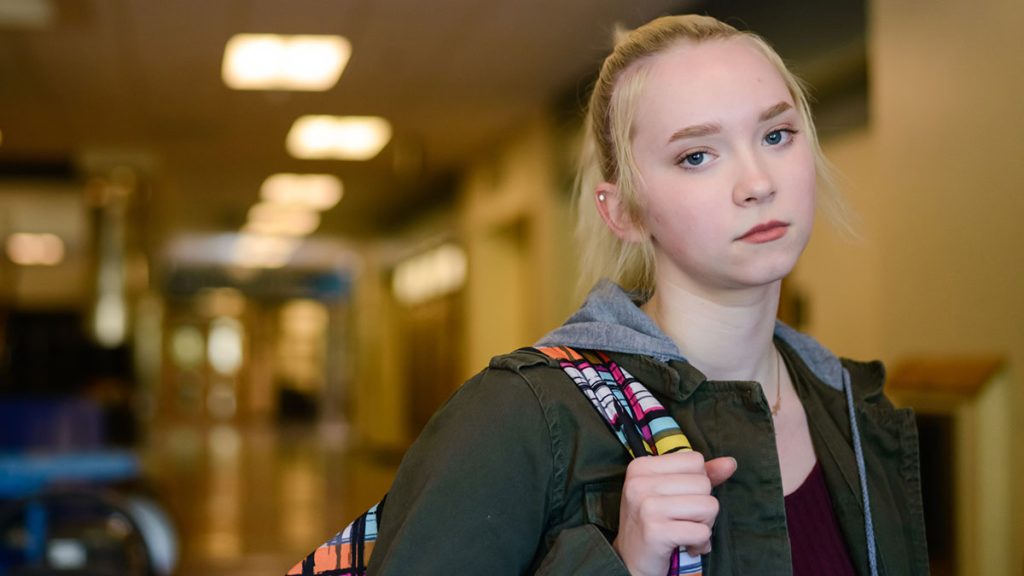 Teen walking in a hallway sad