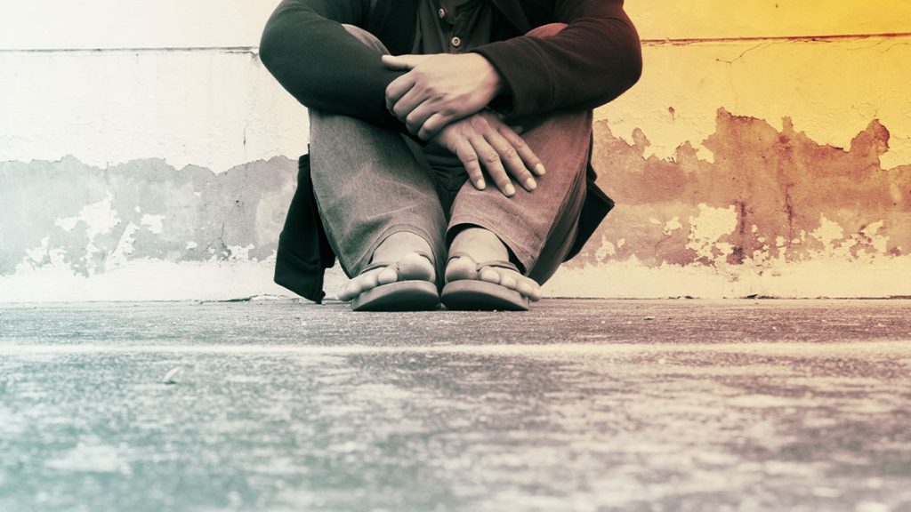 Close up of person sitting on the ground with arms crossed