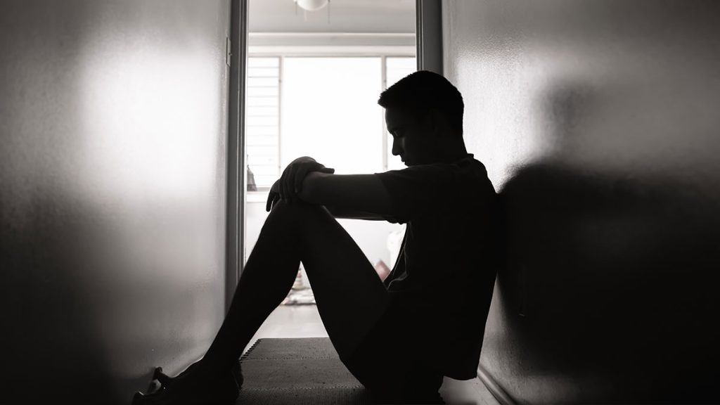 Silhouette of a man in a hallway sitting