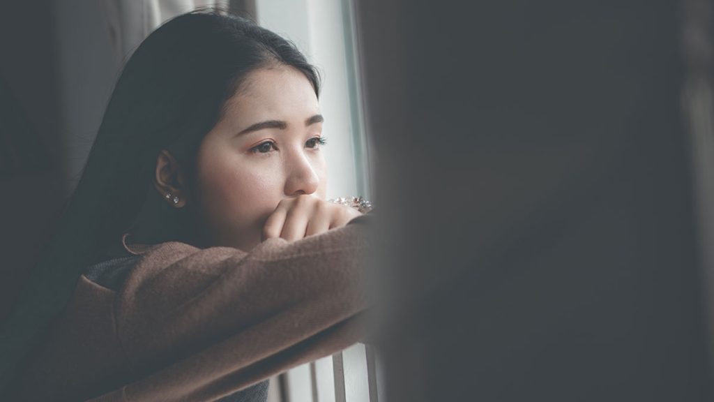 Woman at a window looking sad