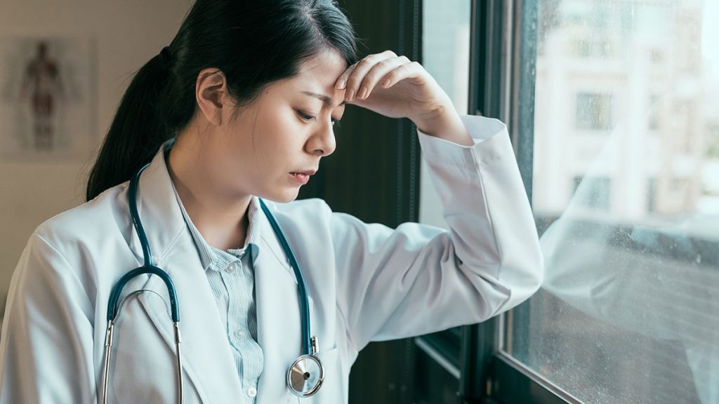Doctor standing at a window stressed