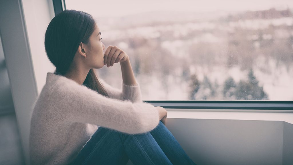 Woman looking out a large window over a city