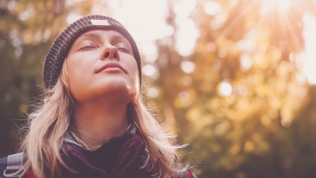 Woman in a forest taking a deep breath