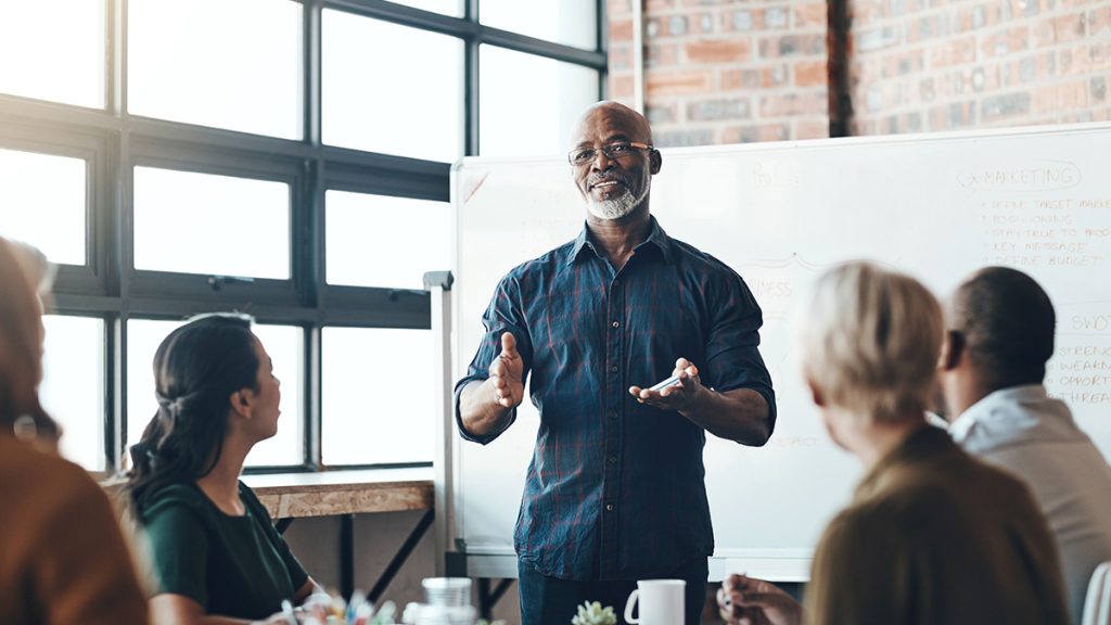 Man presents to a group in front of a board