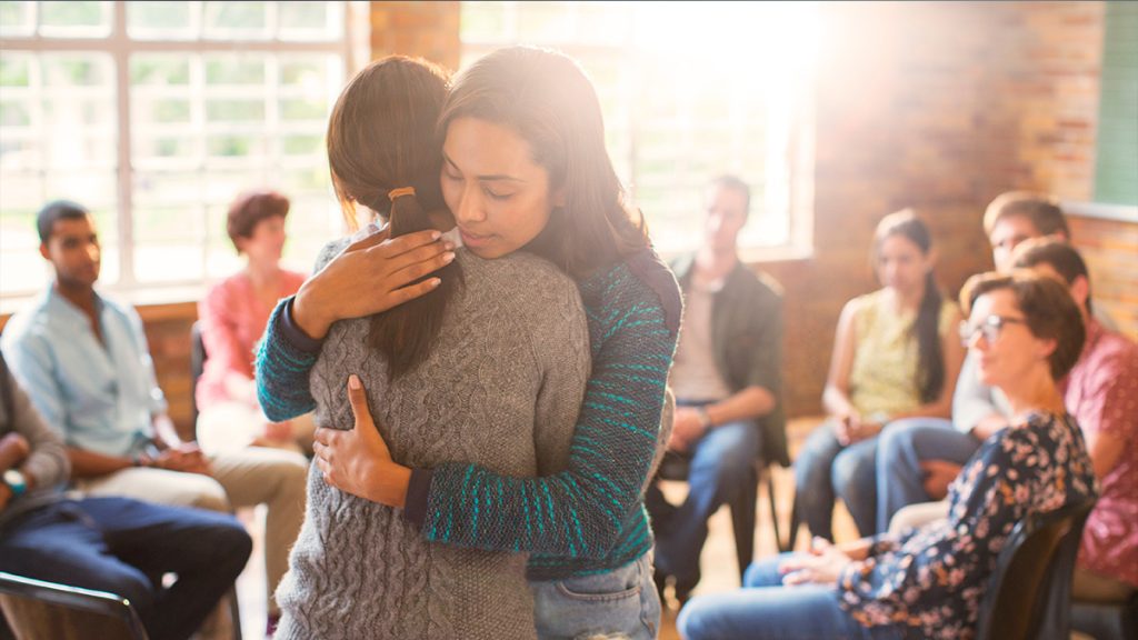 Two people embrace each other at a group