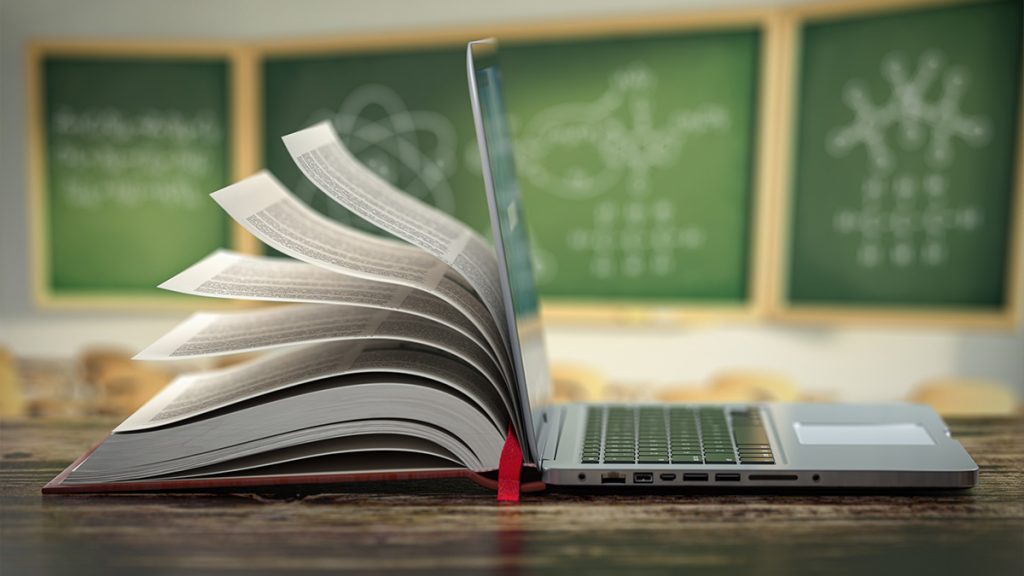 Laptop propped next to an open book
