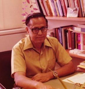 Photo of Dean Hasan sitting at his desk, smiling.