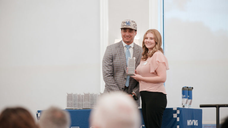 Dean Jay Miller smiles at podium with Sally Levings, recipient of the Outstanding Staff Award
