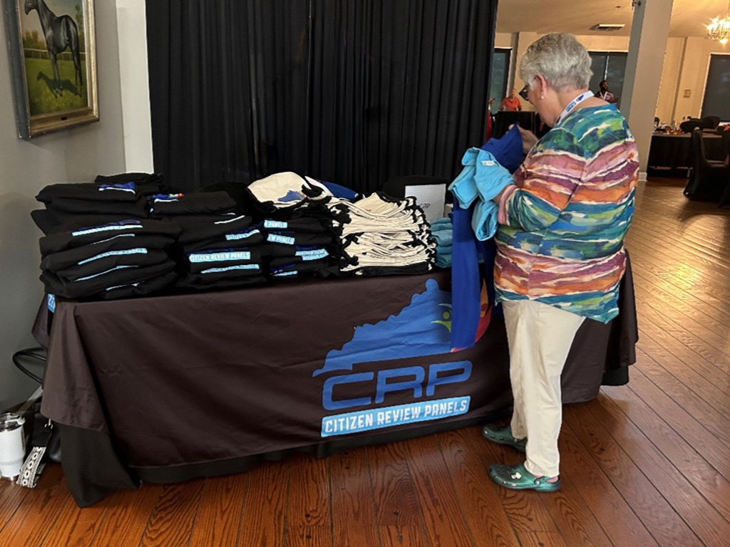 Woman in front of table at CRP conference looking at shirts