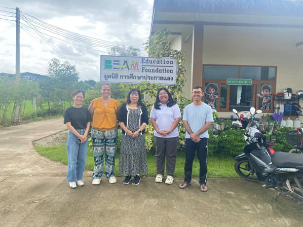 Group of people, including Angelita Lazaro, standing outside the Education Foundation in Thailand.