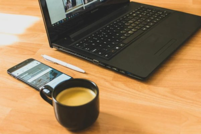 Computer sitting on a table with a full cup of coffee next to it