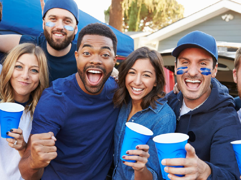 People at a tailgate event holding cups and happy
