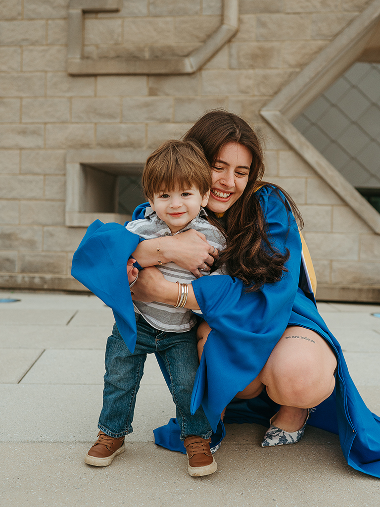 Rachel Campoy in her graduation gown hugging her son
