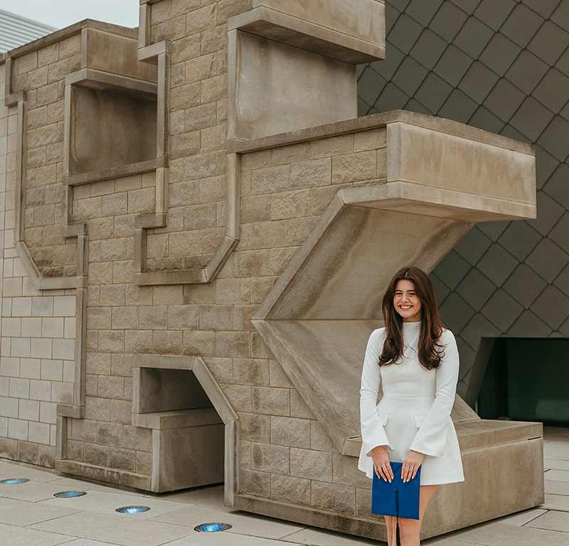 Rachel Campoy posing with her graduation cap in front of the Gatton Student Center.
