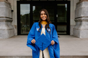 MSW grad Alondra Valle in her graduation robe holding out her grad cap