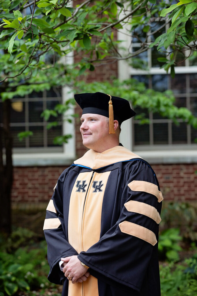 Dr. Holden Dillman, PhD class of 2026 stands in graduation regalia on UKs Campus