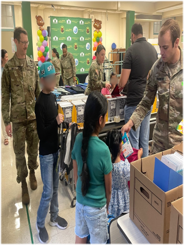 Army-UK Social Work students passing out school supplies to children