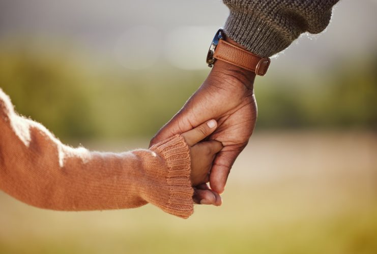 Family, holding hands and girl with father closeup in a park, hands and walking in nature, bond and relax outdoors. Love, trust and parent hands with child in support of trust, peace and unity